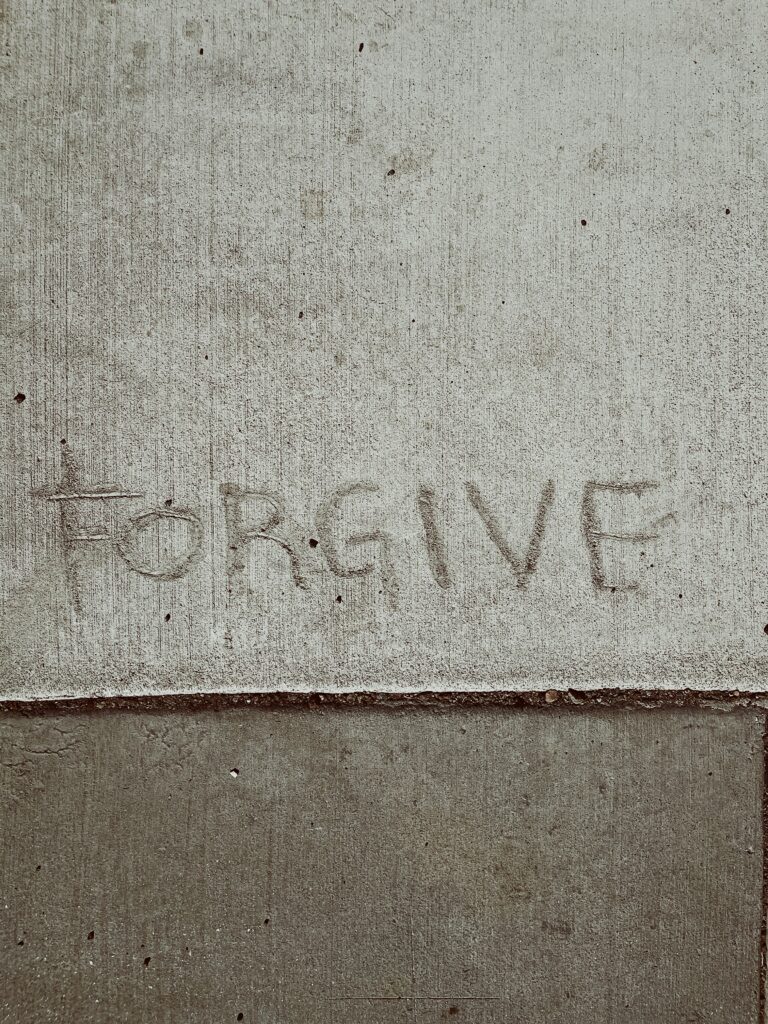The word "forgive" written on pavement
